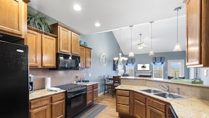A kitchen with wooden cabinets, a black refrigerator, a stove, and a sink. - Branson Vacation Rental | Game Room | Garage | Sleeps 8 (Branson)