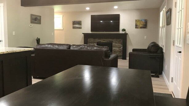 Een moderne woonkamer met een donker houten eettafel, een leren bank en een stenen openhaard.