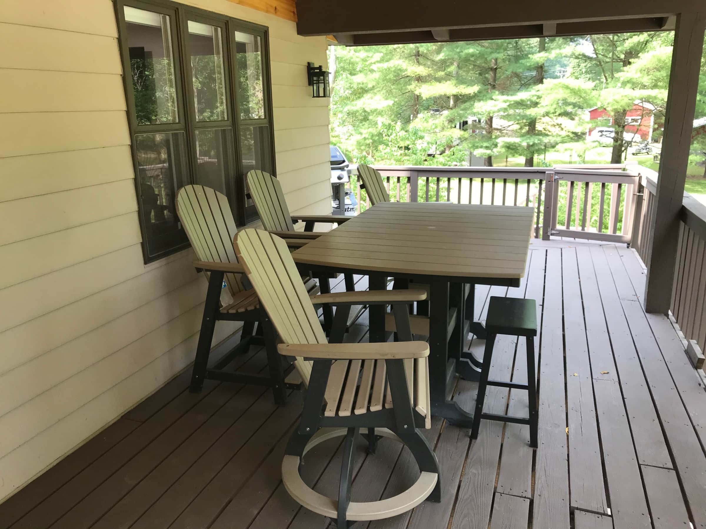 Une terrasse en bois avec une table et des chaises, donnant sur un paysage verdoyant.