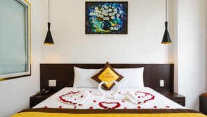 Ein Hotelzimmer mit einem ordentlich bezogenen Bett, einer herzförmigen Dekoration auf dem Bett und einem Gemälde an der Wand.
