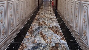 Ein langer Korridor mit Marmorboden und dekorativen Wandverkleidungen.