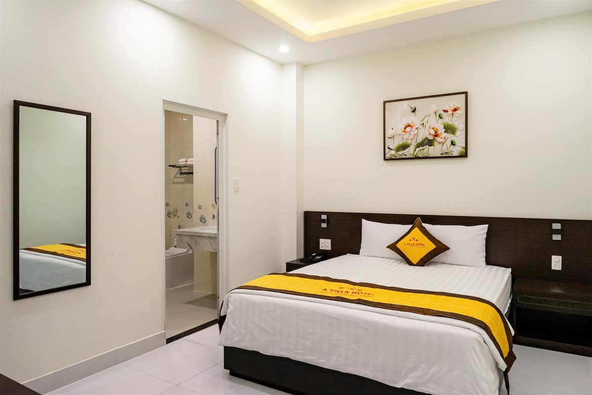 Ein Hotelzimmer mit Bett, Badezimmer und einem Gemälde an der Wand.