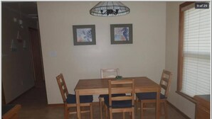 A dining area with a wooden table and chairs, two framed pictures on the wall, and a window with blinds. - ~Free Bike Rides - 3 miles from John Pennekamp - Your Happy Place~ (Key Largo)