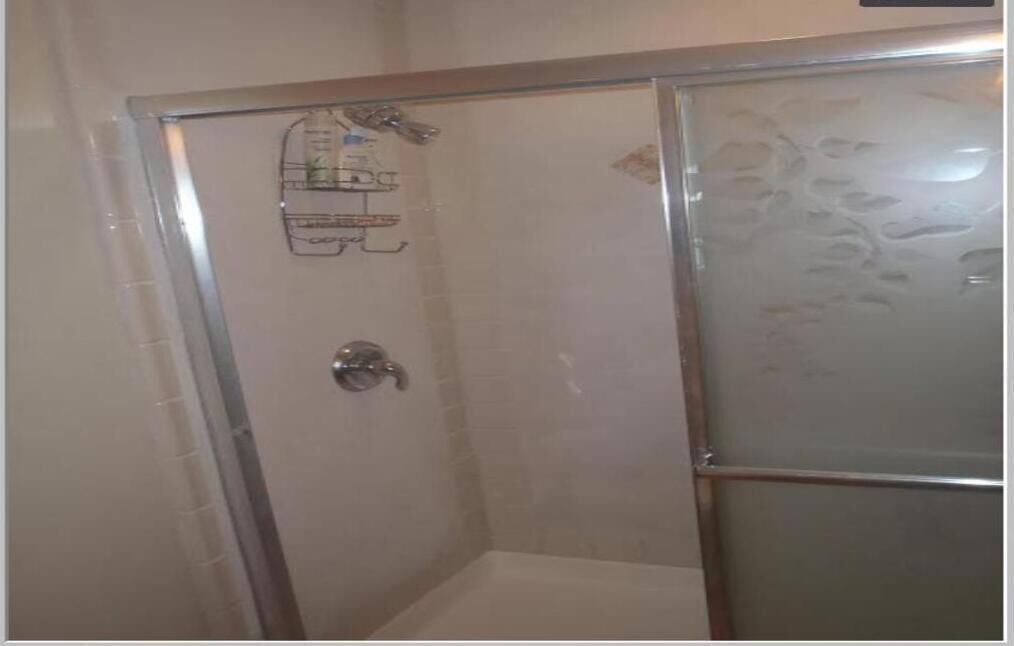 A glass-enclosed shower stall with a showerhead and a handheld shower attachment.