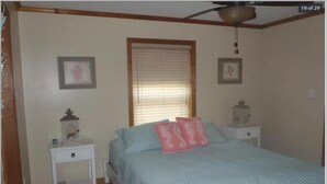 A bedroom with a bed, a nightstand, a bedside table, a window with blinds, and a ceiling fan. - ~Free Bike Rides - 3 miles from John Pennekamp - Your Happy Place~ (Key Largo)