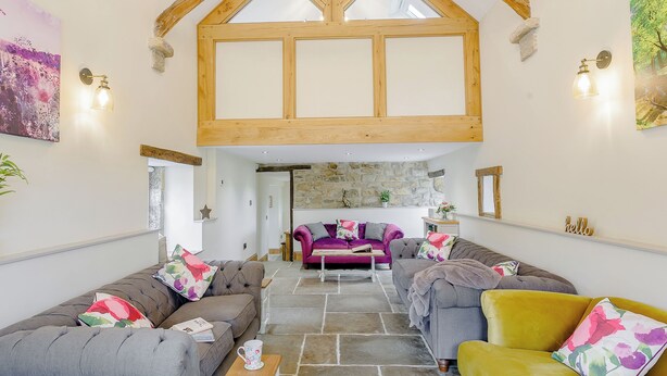 A spacious living area with a vaulted ceiling, stone flooring, and modern furnishings.