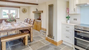 A kitchen with a built-in oven, a dining area with a table set for four, and a large window with a view of greenery.