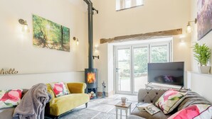 A living room with a fireplace, sofas, a television, and a large window.