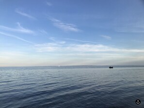 Ein ruhiges Meer mit einem kleinen Boot in der Ferne und einem klaren Himmel.