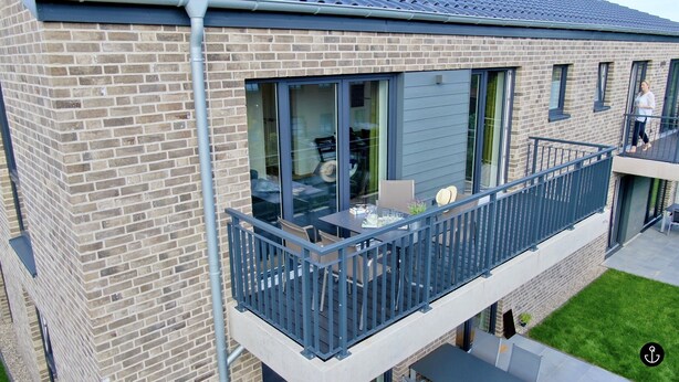 A modern apartment with a balcony, large windows, and a brick facade. - Refugium 3 (Kellenhusen)