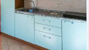 Eine Küche mit hellblauen Schränken, einem Holzkabinett, einer Spüle und einer Arbeitsplatte.