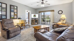 Ein Wohnzimmer mit Relaxsessel, Ledersofa, Couchtisch aus Holz und Fernseher.