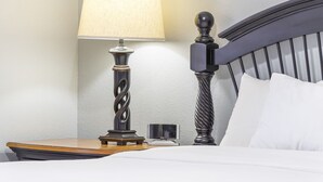 Ein ordentlich bezogenes Bett mit weißen Bettwäsche, ein Nachttisch mit Lampe und ein moderner Kopfteil.