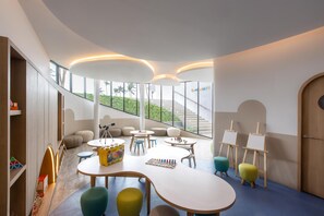 A modern children's play area with tables, chairs, and art supplies.