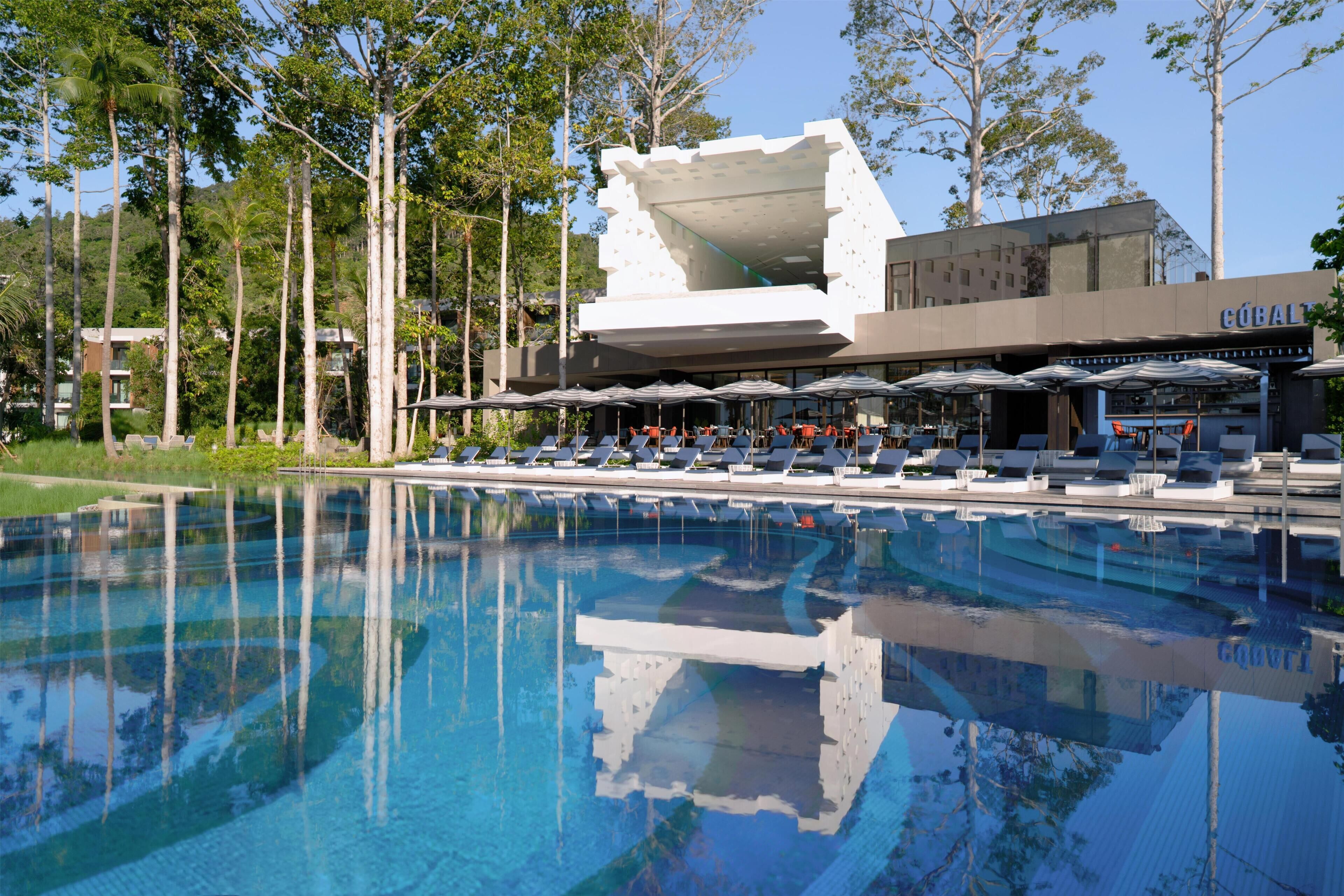 Un hotel moderno con piscina, zona de estar exterior y un diseño arquitectónico distintivo.