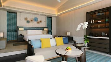 A modern hotel room with a bed, sofa, coffee table, and a small dining area.