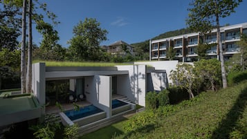 A modern house with a swimming pool, surrounded by lush greenery and a hillside.