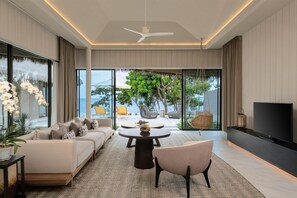 A modern living room with a sofa set, a round coffee table, a TV, and a view of the outdoors.