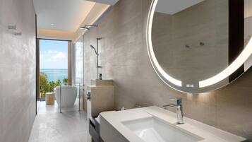 Une salle de bain moderne avec un grand miroir, une baignoire et une vue sur la mer.