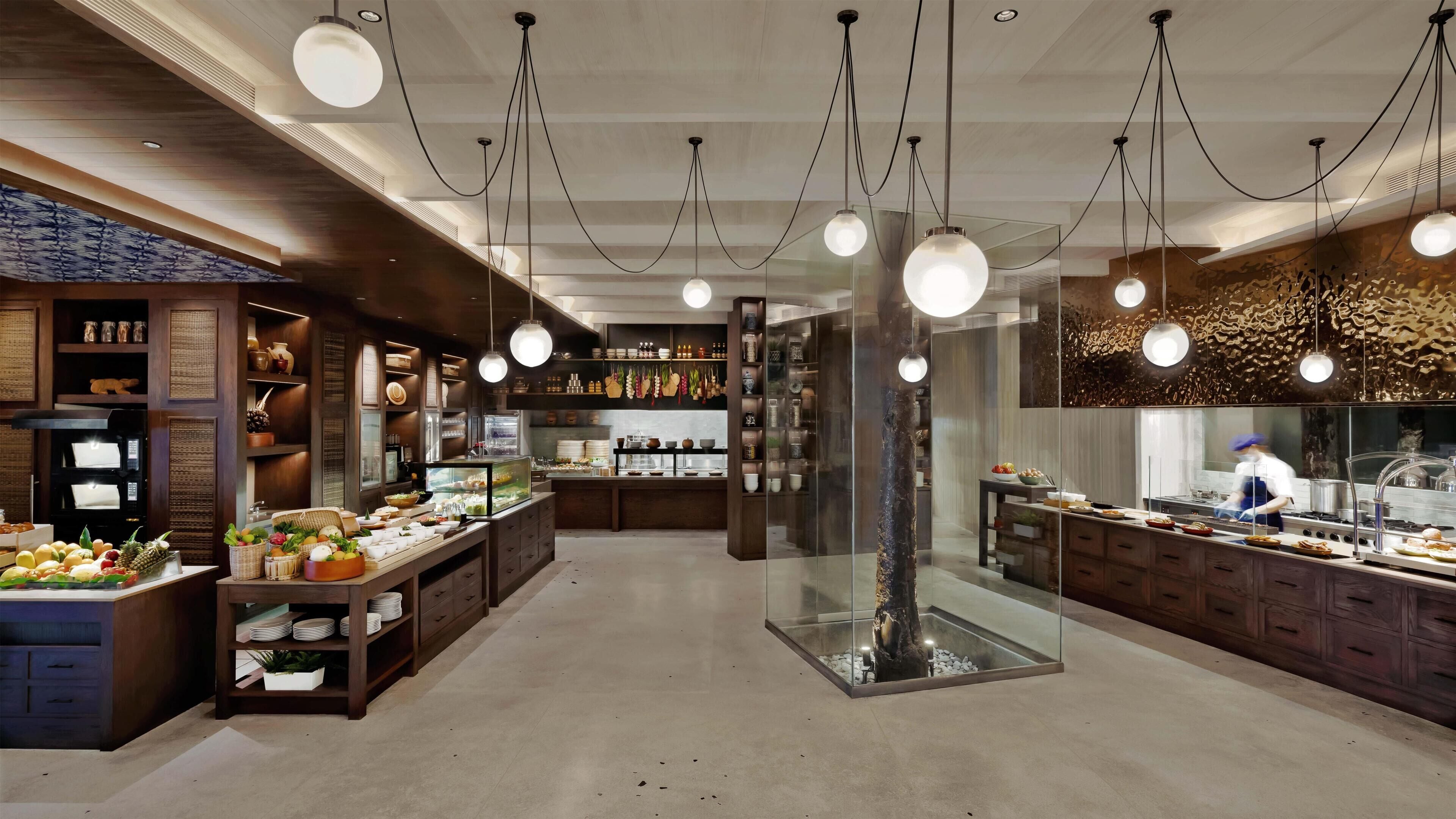 Un interior de restaurante moderno con armarios de madera, una zona central de servicio y lámparas colgantes.