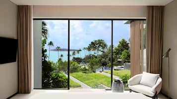 A modern room with a large sliding glass door, a white sofa, a floor lamp, and a flat-screen TV.