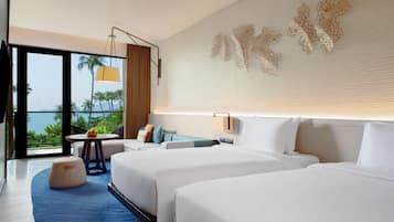 A hotel room with two beds, a round table, a view of palm trees, and a decorative wall piece.