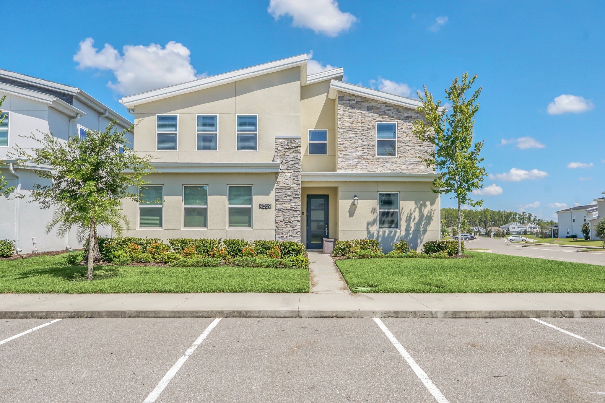 Un bâtiment moderne à deux étages, doté d’une façade en pierre, de nombreuses fenêtres et d’une pelouse bien entretenue.