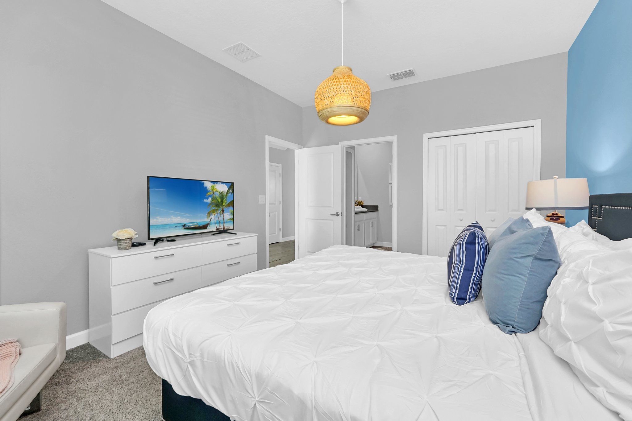 Een slaapkamer met een bed, een televisie, een dressoir, een kledingkast en een hanglamp.