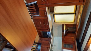 A compact kitchen with wooden cabinets, a built-in oven, a sink, and a dining table with chairs.