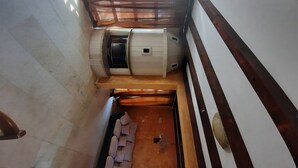A narrow room with a wooden floor, a white cabinet, and a window with blinds.