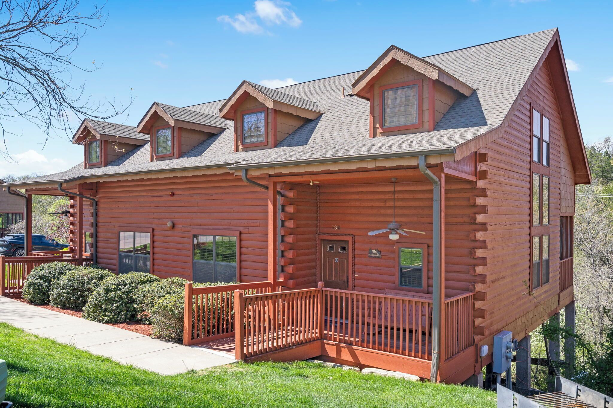 A log cabin with a porch, multiple windows, and a chimney.