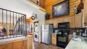 A kitchen with wooden cabinets, a stainless steel refrigerator, a microwave, and a stove. - Woodland Retreat for 6 | Cozy Fireplace + Pool Access (Branson)
