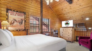 A wooden cabin room with a bed, a dresser, a chair, and a poster on the wall. - Woodland Retreat for 6 | Cozy Fireplace + Pool Access (Branson)
