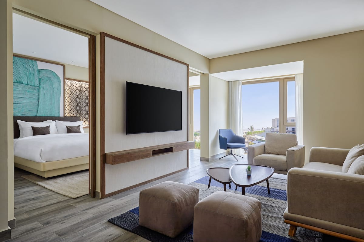 A modern hotel room with a bed, a TV, a sofa, and a coffee table.