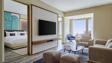 A modern hotel room with a bed, a TV, a sofa, and a coffee table.