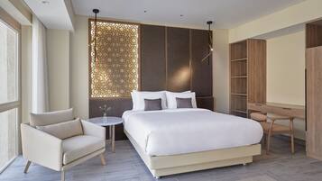 A modern bedroom with a large bed, a chair, a desk, and a wardrobe.