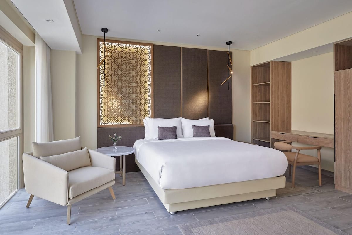 A modern bedroom with a large bed, a desk, a chair, and a small table.
