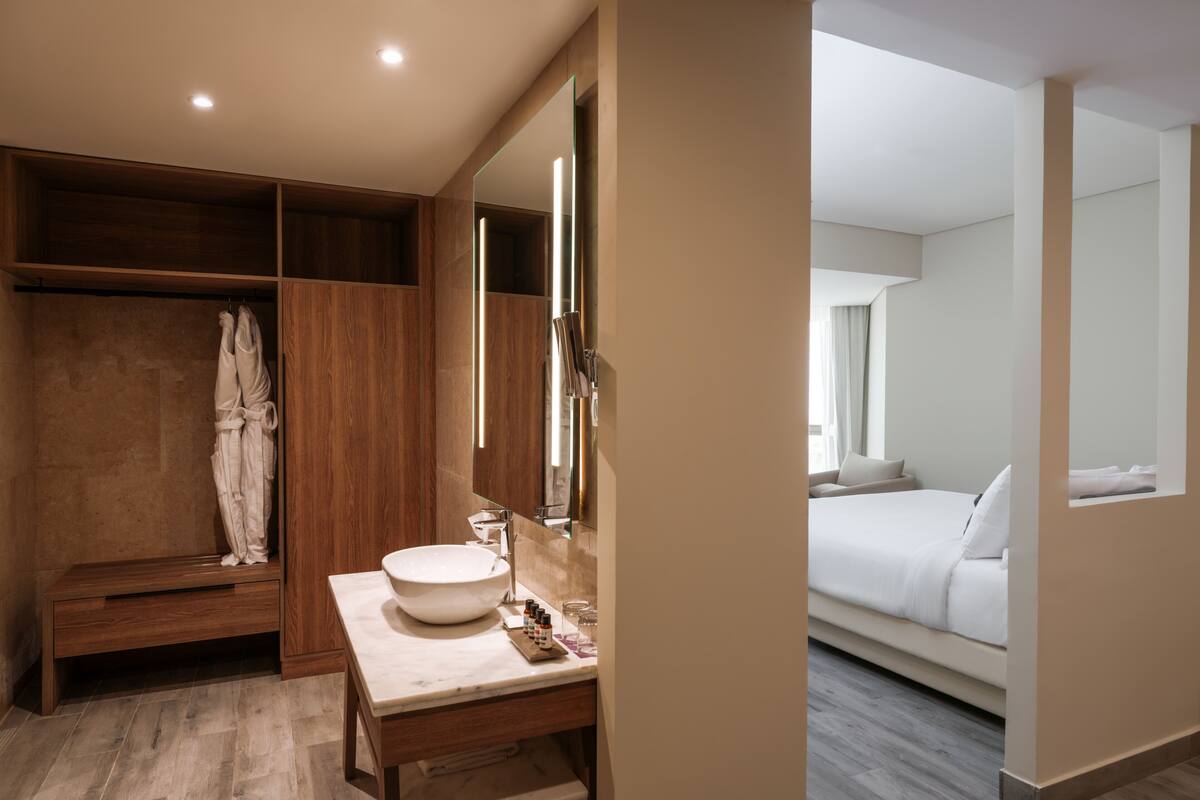A modern bathroom with a large mirror, wooden vanity, and a bathtub.