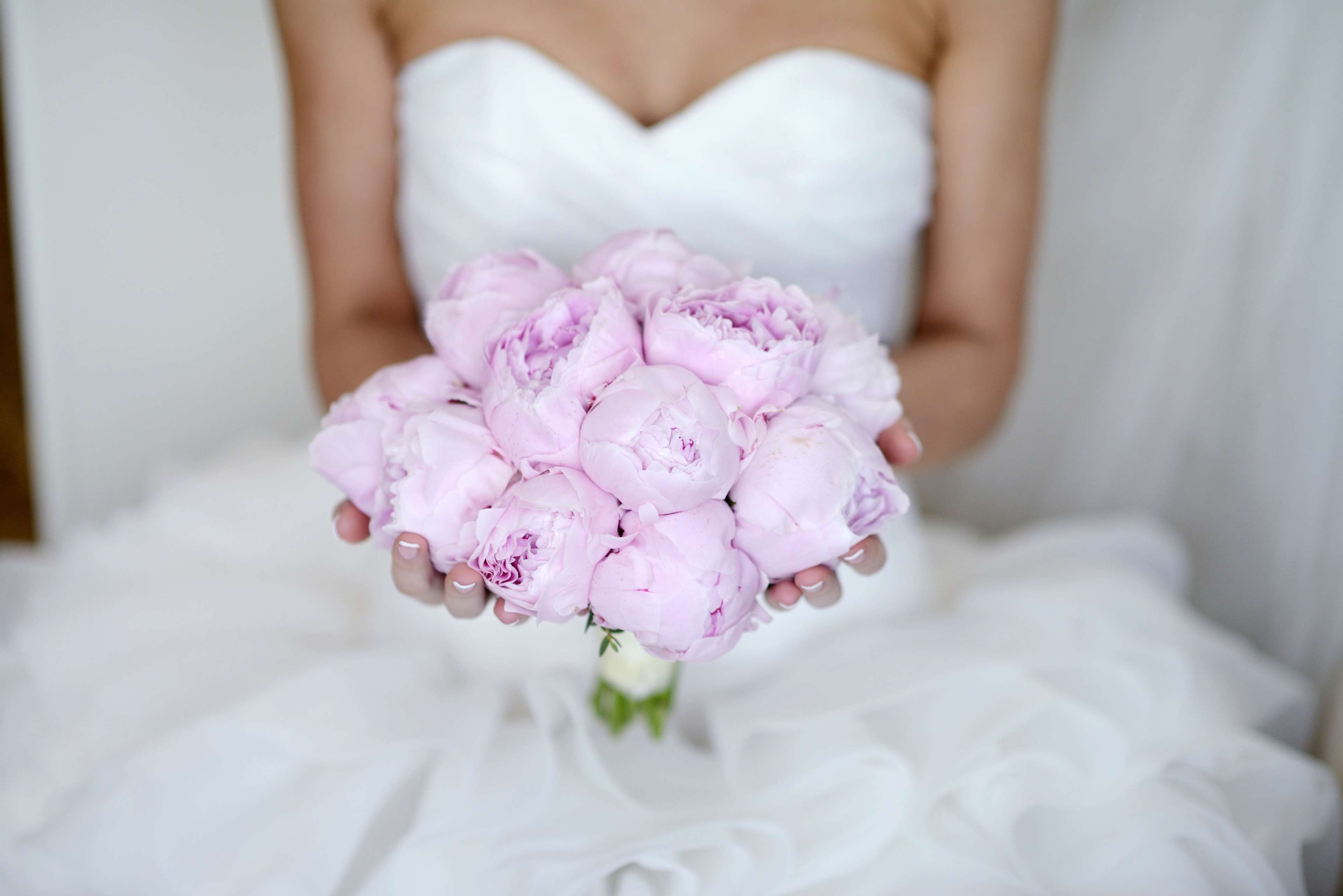 A person holding a bouquet of pink flowers.