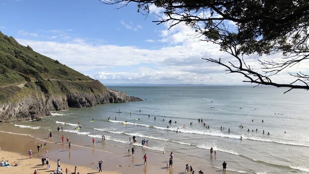 Une plage où l’on peut voir des gens faire de la planche à voile et se promener le long du rivage.