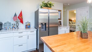 A modern kitchen with a stainless steel refrigerator, a wooden countertop, and a small dining area.