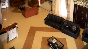 A spacious living area with a high ceiling, a balcony with a railing, and a chandelier. - Osaah Bema lodge (Antoa)