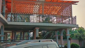 A balcony with a lattice structure and a car parked below. - Osaah Bema lodge (Antoa)