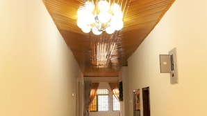 A hallway with a wooden ceiling and a chandelier, leading to a room with a window and a door. - Osaah Bema lodge (Antoa)