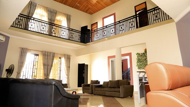 A spacious living area with a high ceiling, a balcony with a railing, and a staircase leading to an upper level. - Osaah Bema lodge (Antoa)