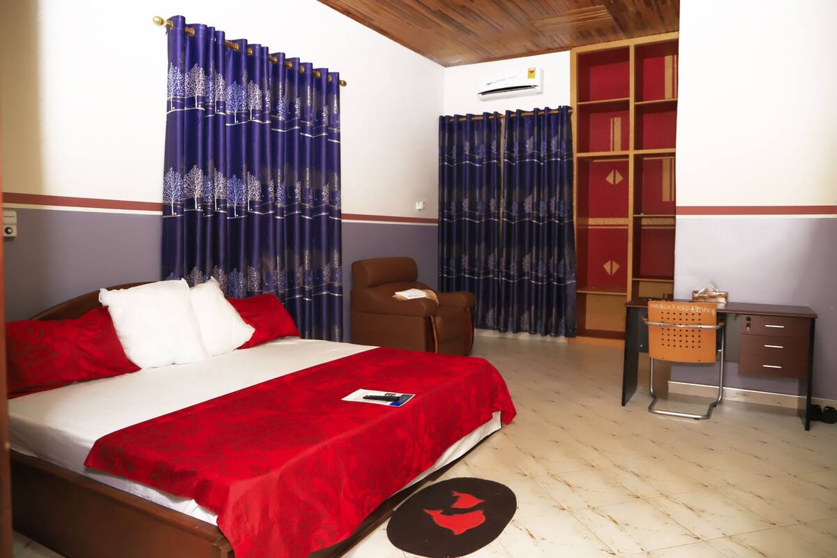 A bedroom with a bed, a chair, a desk, and a wardrobe.