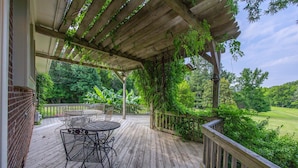 Um deck de madeira com pérgola, móveis de exterior e vista para um campo de golfe.