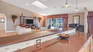 Un vaste espace de vie comprenant un grand îlot central, un téléviseur à écran plat et une table à manger.