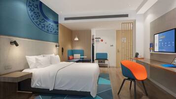 Habitació d'hotel moderna amb llit, zona de seients, escriptori i televisió.