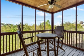 Relax in a serene outdoor space with a wooden deck, ceiling fan, and comfortable seating for two.